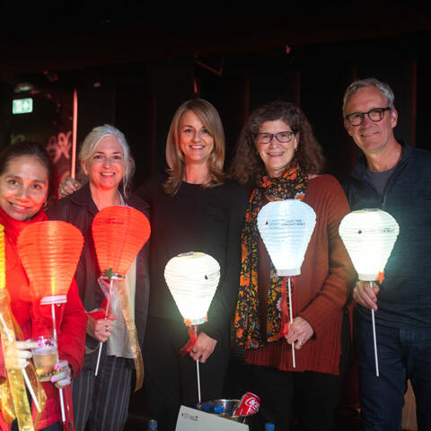 A group shot of 5 people with all of their lanterns lit at night.